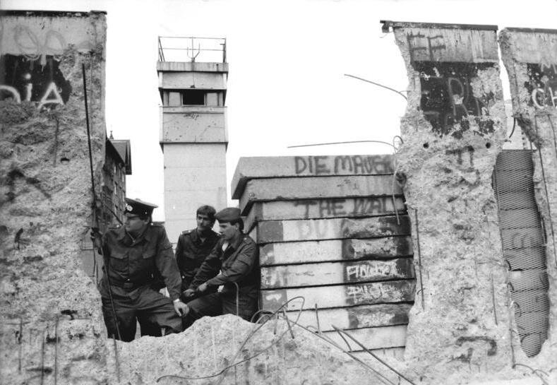 Border soldiers and a watchtower beside a hole in the Berlin Wall, April 1990