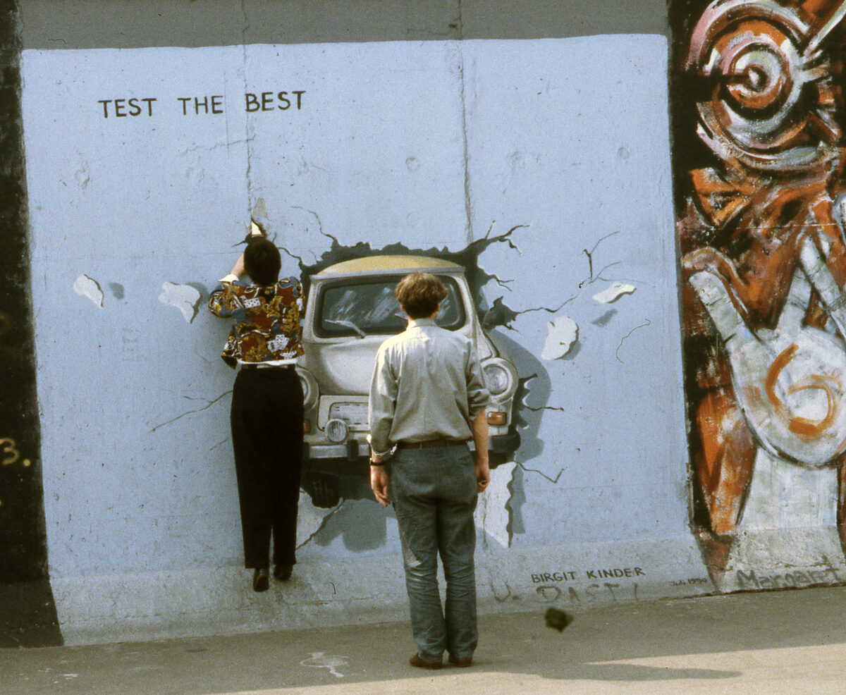 Birgit Kinder's Trabant mural 'Test the Best' breaking through the Berlin Wall, photographed at the East Side Gallery in 1990