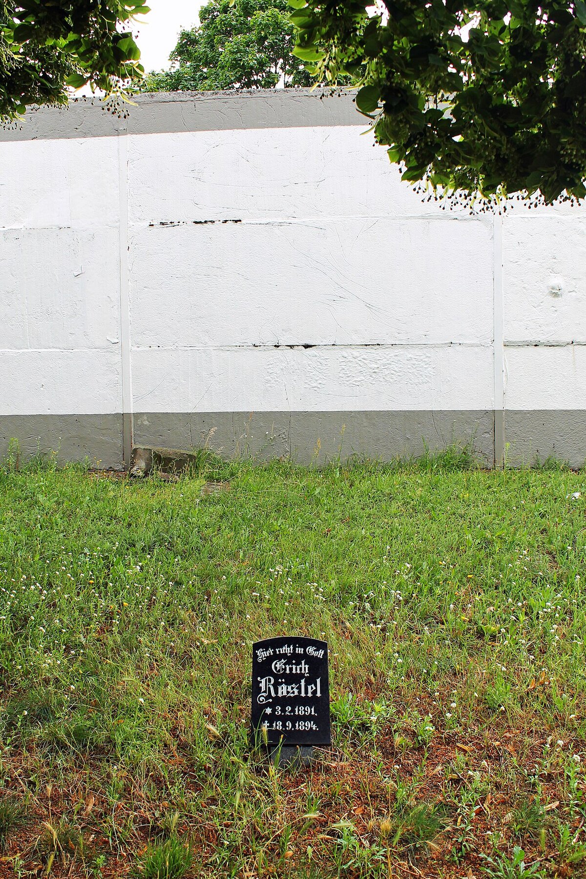 Ein Grabstein vor der Mauer am Invalidenfriedhof