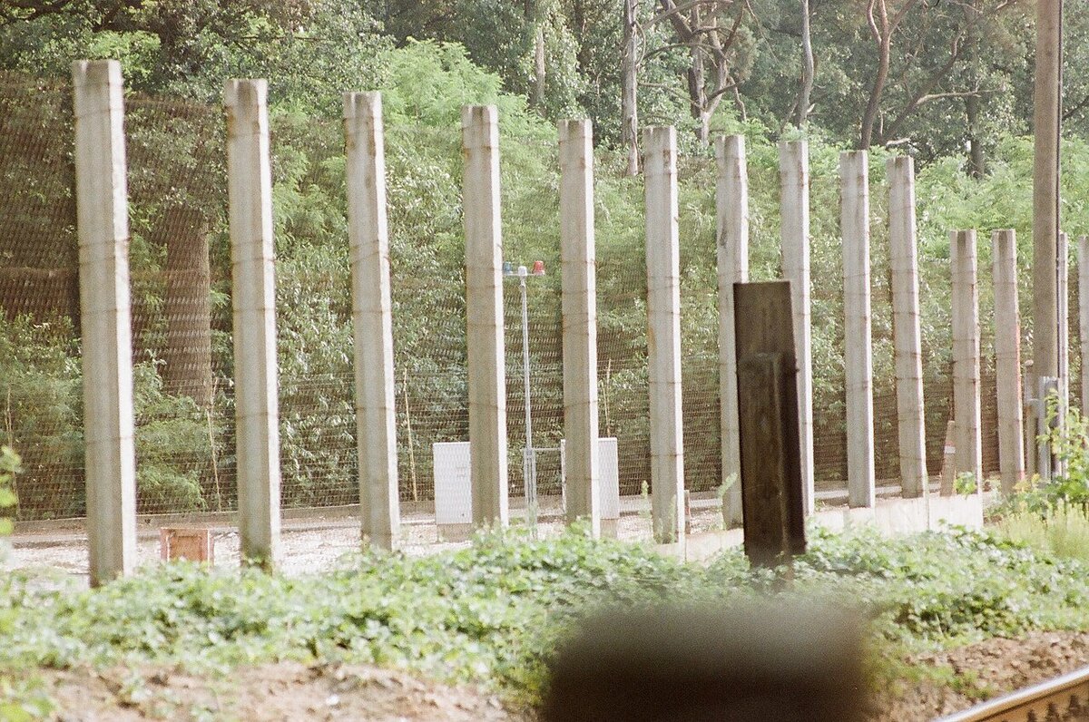 Metal border fence surrounding Steinstücken railway line, with railway alarm